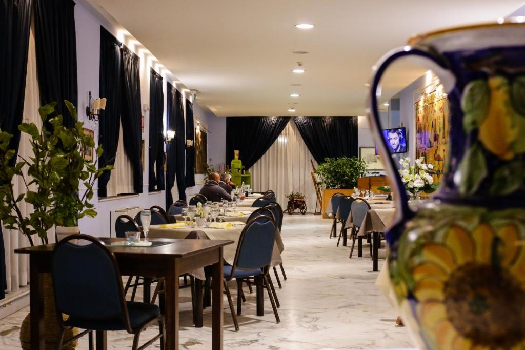 un restaurant avec des tables, des chaises et un vase dans l'établissement Miramare Hotel, à Catane