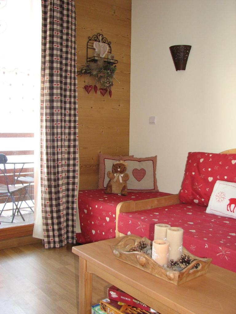 - un salon avec un canapé rouge et un ours en peluche sur une table dans l'établissement Appt Le Hameau Des Rennes 4 étoiles Pieds des pistes Piscine Intérieure Extérieure, à Vars