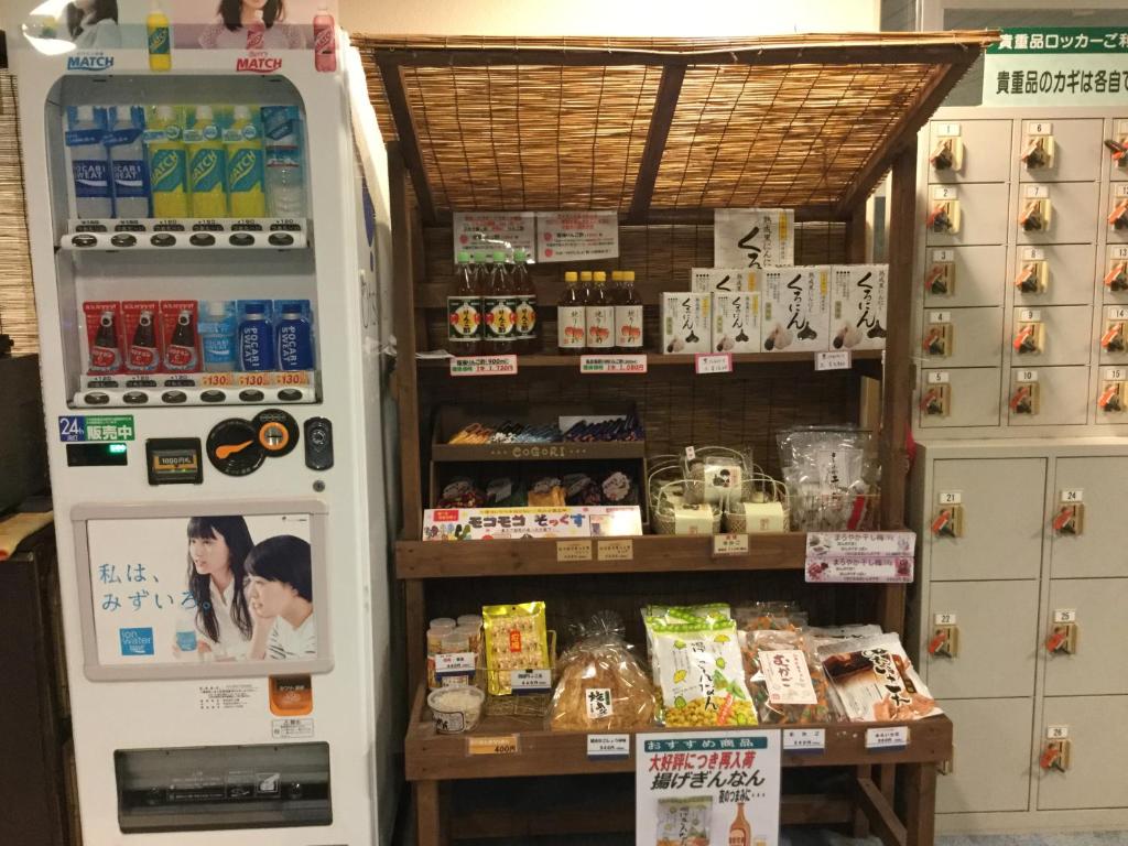 - un réfrigérateur dans un magasin à côté d'une étagère avec de la nourriture dans l'établissement シーパの湯 Seapa no Yu, à Matsuyama