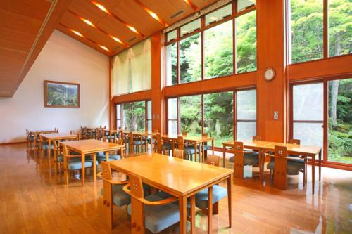 une salle à manger avec tables, chaises et fenêtres dans l'établissement Shiki Resort Hida Takayamaso, à Takayama
