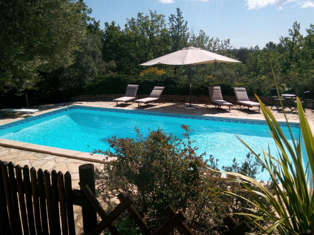 une piscine avec des chaises et un parasol dans l'établissement Gite Les Oliviers, à Cotignac