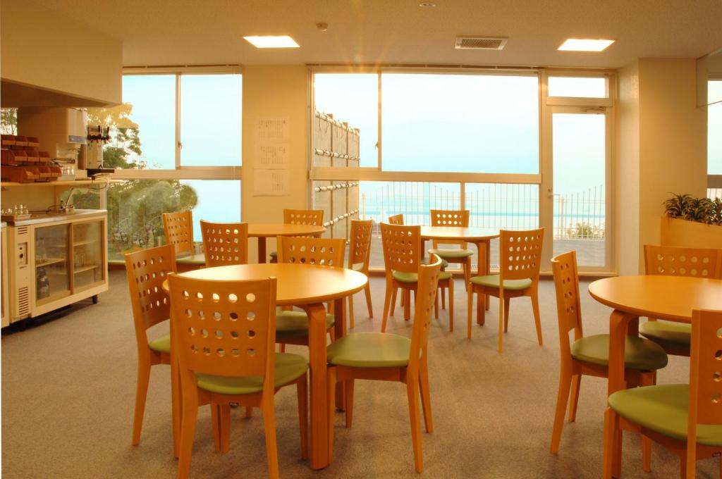 une salle à manger avec tables, chaises et fenêtres dans l'établissement シーパの湯 Seapa no Yu, à Matsuyama