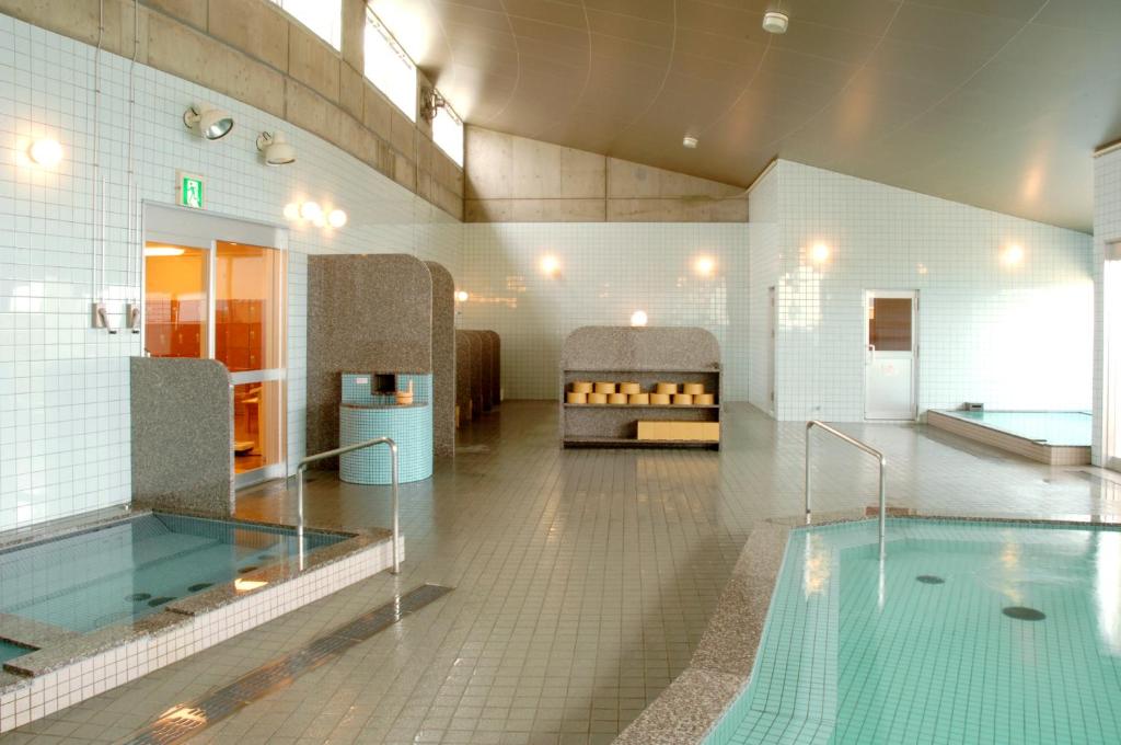 - une salle de bains avec une piscine dans un bâtiment dans l'établissement シーパの湯 Seapa no Yu, à Matsuyama