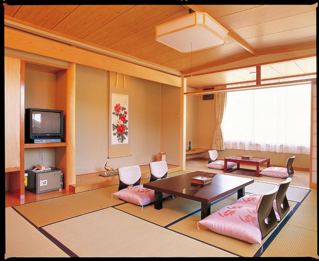 - un salon avec une table, des chaises et une télévision dans l'établissement Yuttarino-Sato Inaka, à Achi