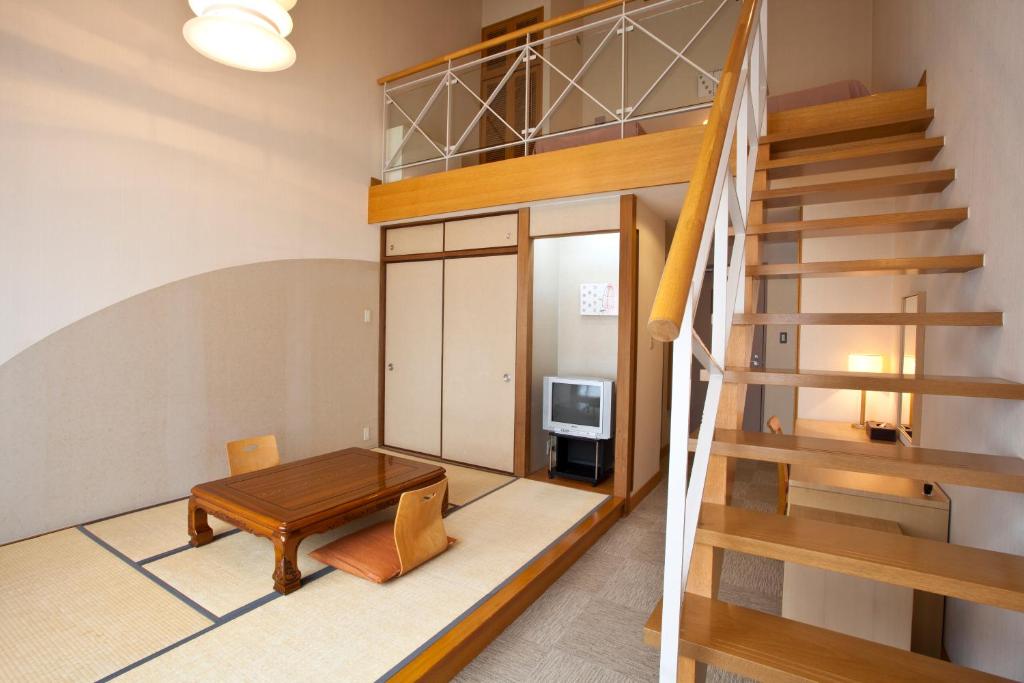 Cette chambre dispose d'une table en bois et d'un escalier. dans l'établissement Shiki Resort Aisonet Kusatsu, à Kusatsu