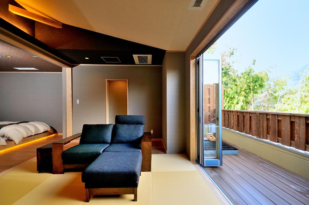 Cette chambre dispose d'un balcon avec un canapé et un lit. dans l'établissement Tensui Saryo, à Hakone