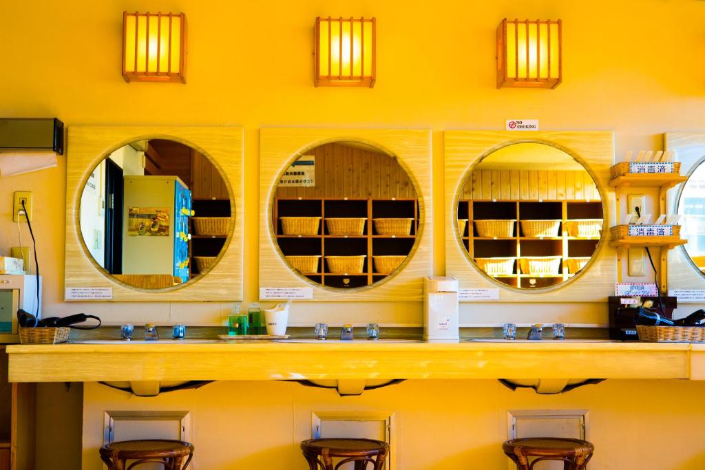 une salle de bains avec 4 miroirs sur un mur jaune dans l'établissement Hotel Sekitei, à Fuefuki