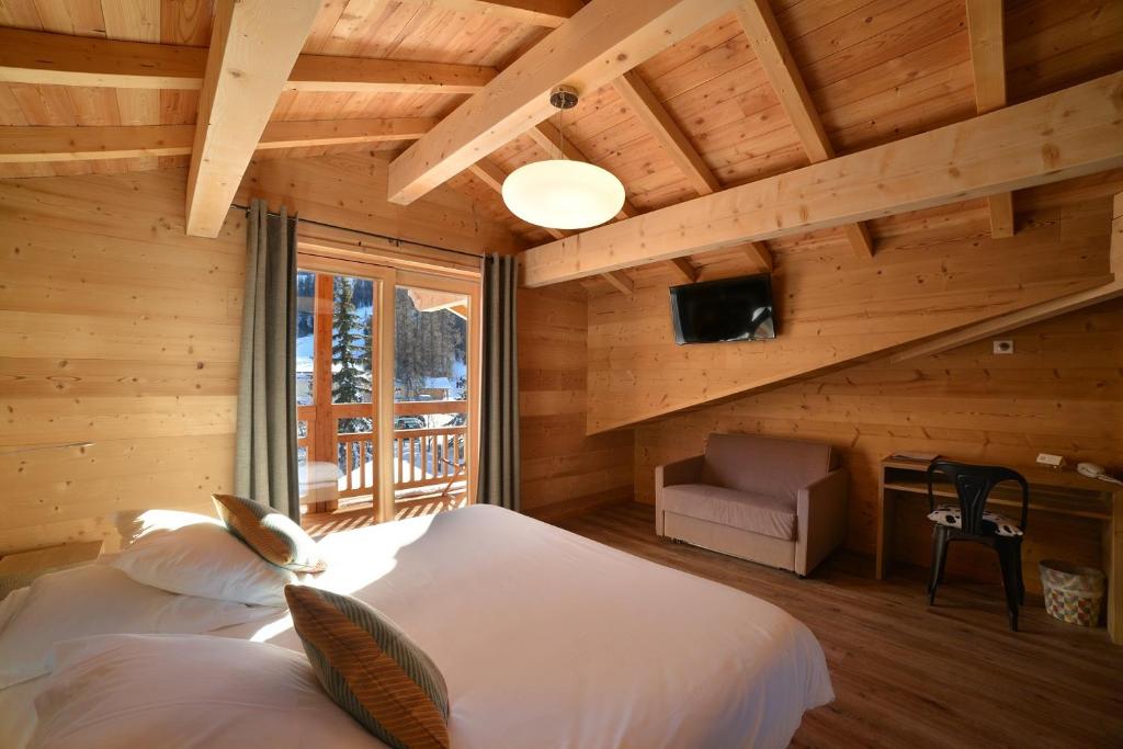 une chambre avec deux lits dans une cabane en rondins dans l'établissement Hotel & Restaurant Les Escondus, à Vars