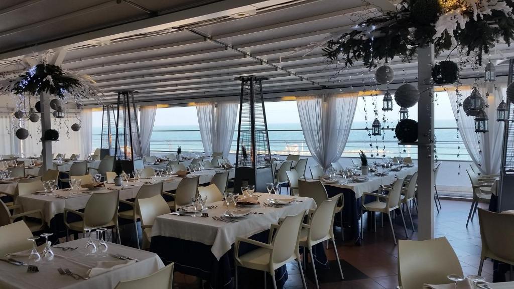 une salle de banquet avec des tables et des chaises blanches dans l'établissement Hotel Salsello, à Bisceglie