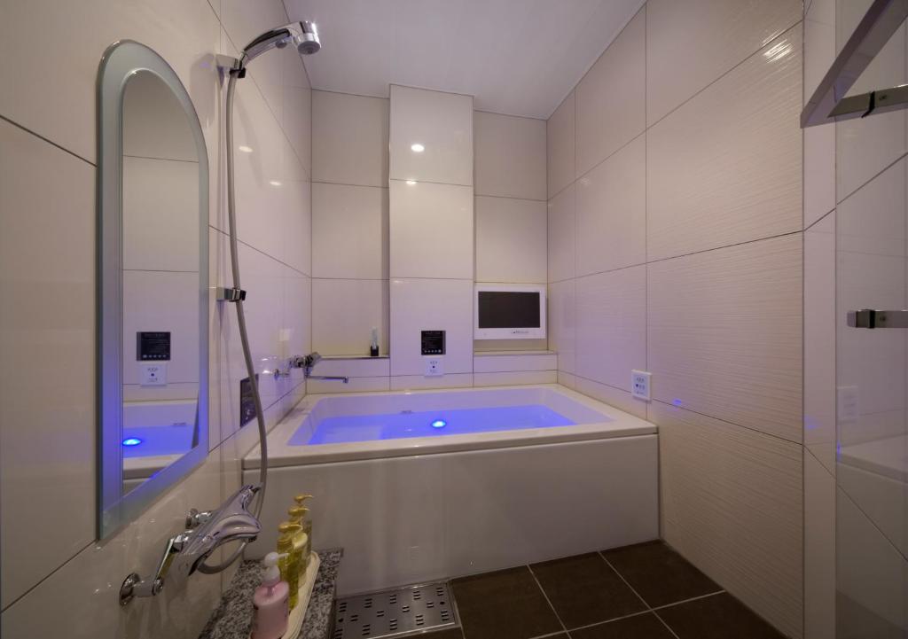 La grande salle de bains est pourvue d'une baignoire, d'une fenêtre et d'un miroir. dans l'établissement JEWEL HOTEL LUXURY MODERN (Adult Only), à Miyoshi