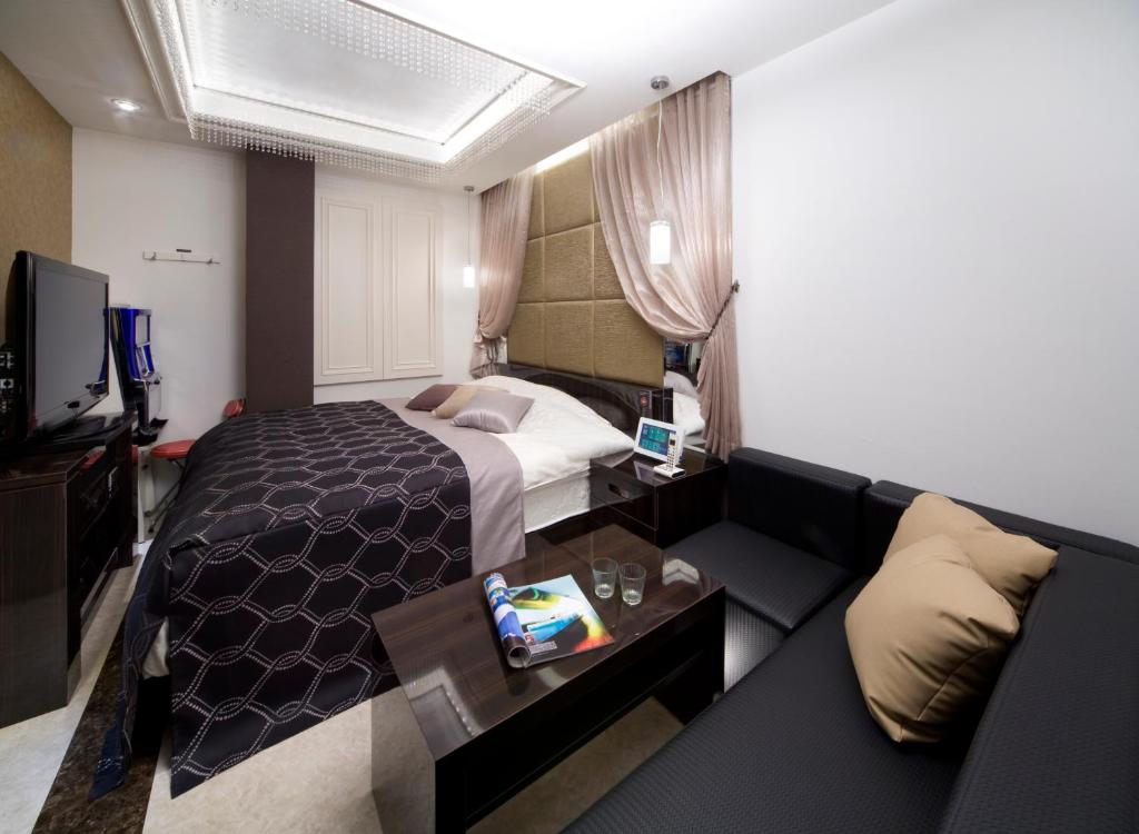une chambre d'hôtel avec un lit et un canapé dans l'établissement JEWEL HOTEL LUXURY MODERN (Adult Only), à Miyoshi