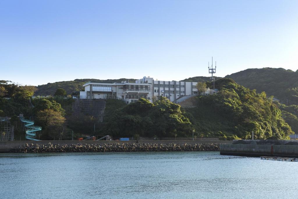 un grand bâtiment sur une colline à côté d'un plan d'eau dans l'établissement Ikijimaso, à Iki
