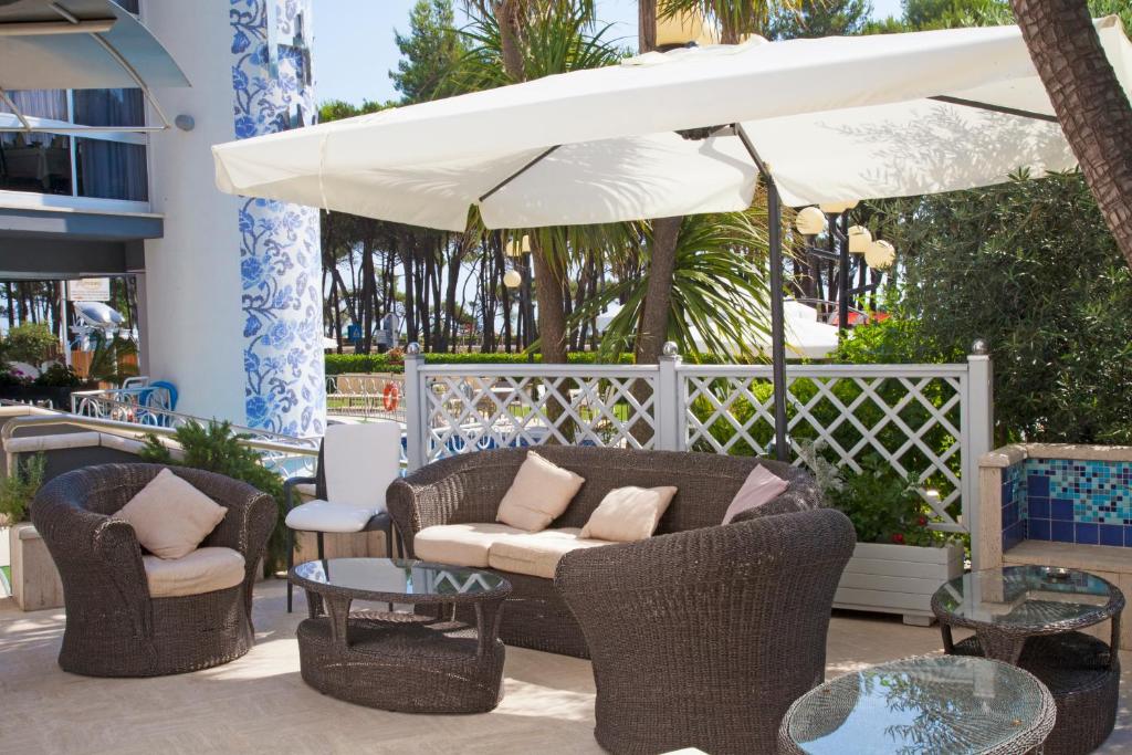 une terrasse avec des chaises, des tables et un parasol dans l'établissement Hotel Meripol, à Alba Adriatica