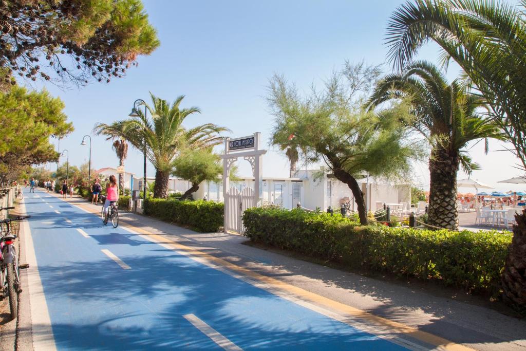 une personne à vélo dans une rue bordée de palmiers dans l'établissement Hotel Meripol, à Alba Adriatica
