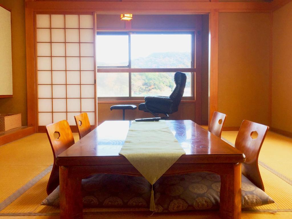 une table et des chaises dans une pièce avec une fenêtre dans l'établissement Hoshi Meguri, à Shimoda 7 autres photos