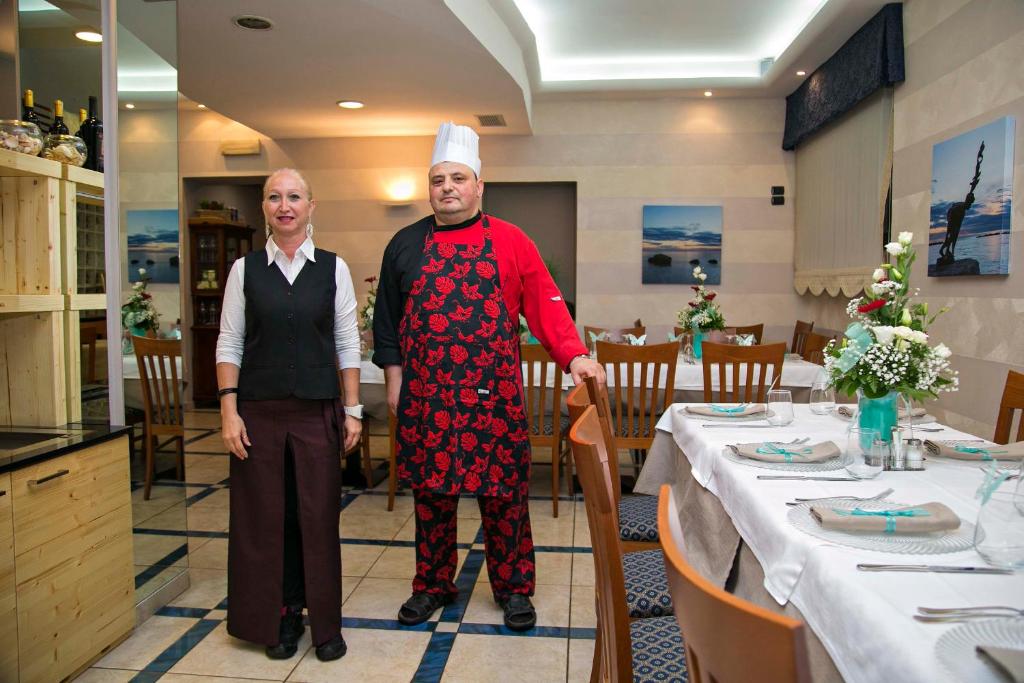 Un homme et une femme sont debout dans un restaurant dans l'établissement Hotel lo Squalo, à Grottammare