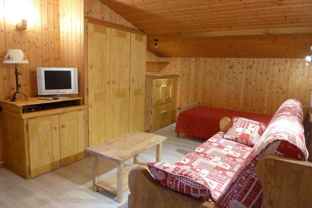 - un salon avec un canapé et une télévision dans une cabine dans l'établissement Chalet "les Arcosses", à La Giettaz