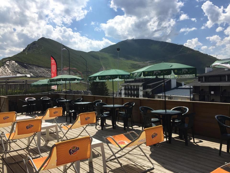 une terrasse avec des tables, des chaises et des parasols verts dans l'établissement Ô CHALET 1700 chalet FFS, à Saint-Lary-Soulan