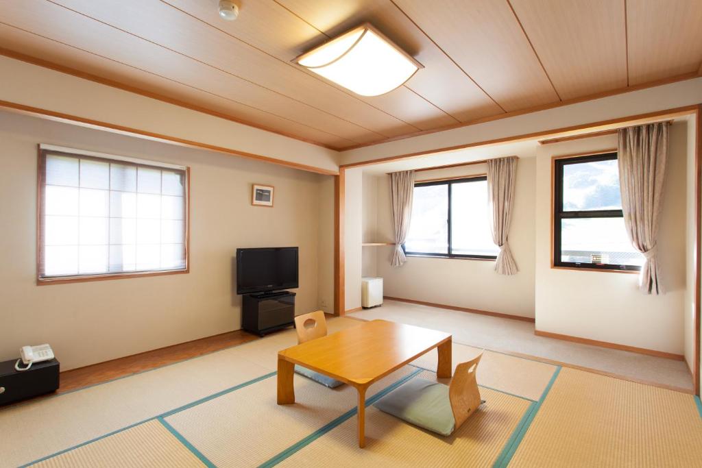 un salon avec une table et une télévision dans l'établissement Schole Hakuba, à Hakuba
