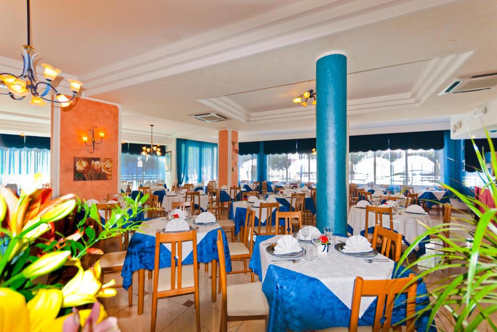 un restaurant avec des tables et des chaises et un pôle bleu dans l'établissement Hotel Gimm, à Bibione