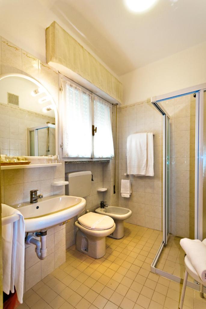 une salle de bain avec un lavabo, des toilettes et une douche dans l'établissement Hotel Gimm, à Bibione