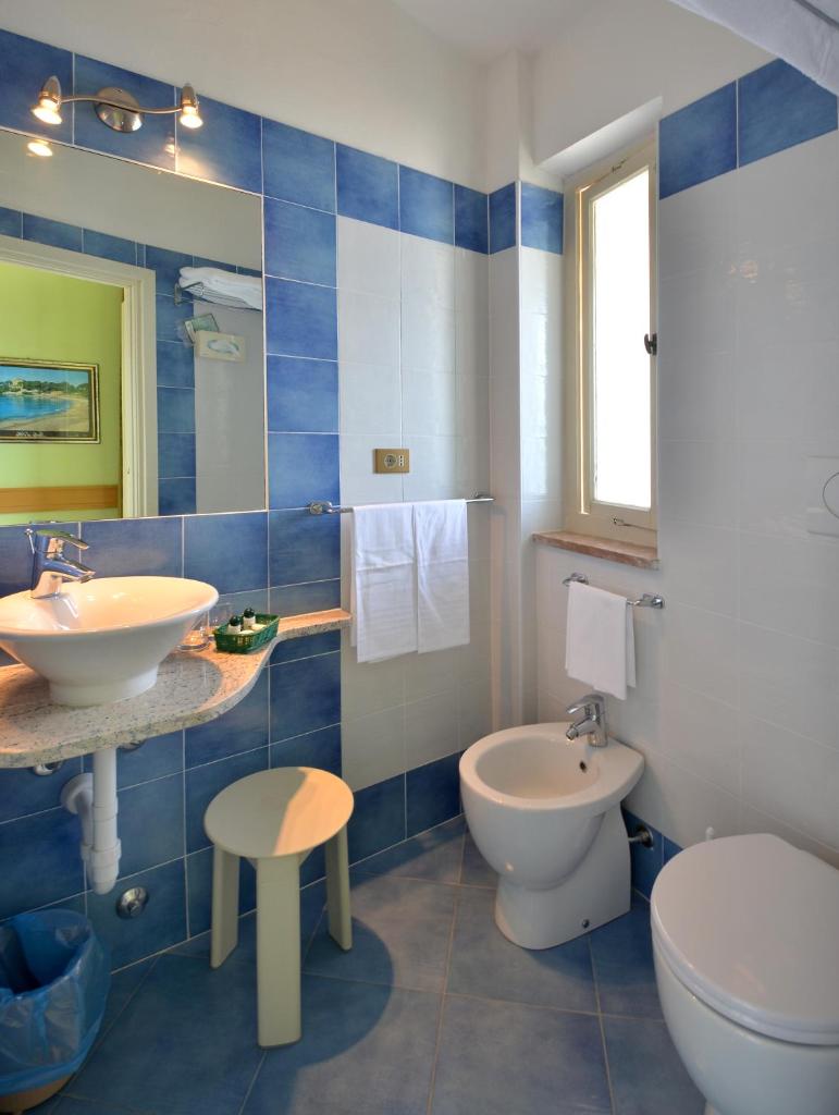 La salle de bains bleue et blanche est pourvue d'un lavabo et de toilettes. dans l'établissement Hotel Stella Maris, à Capoliveri