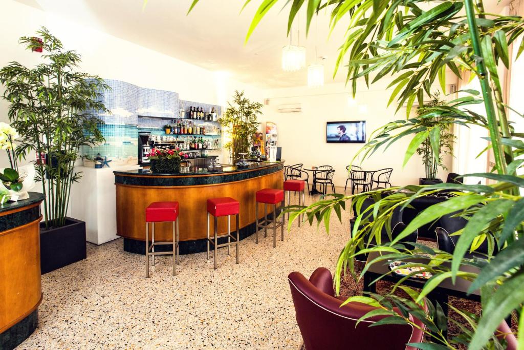 - un bar avec des chaises rouges dans une pièce ornée de plantes dans l'établissement Hotel Confort, à Cattolica