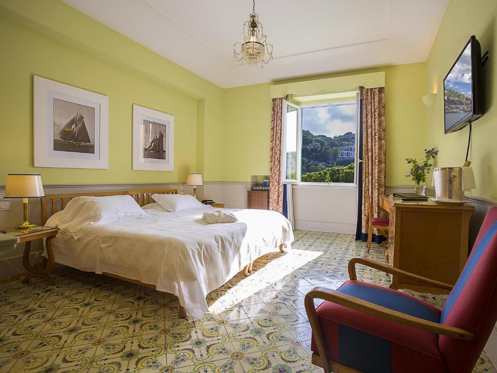 une chambre avec un lit, une fenêtre et une chaise dans l'établissement Regina Isabella-Resort Spa Restaurant, à Ischia