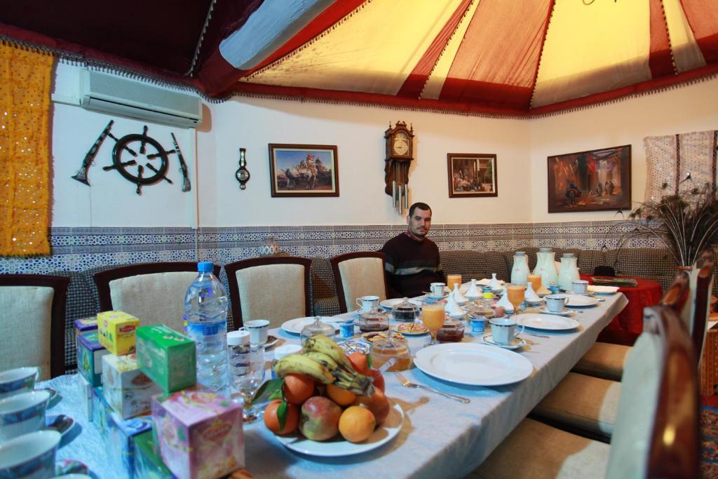Un homme assis à une longue table avec de la nourriture sur elle dans l'établissement Riad Asma, à Taroudant
