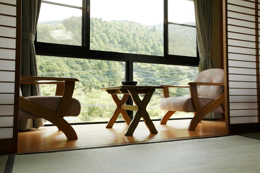 une chambre avec deux chaises et une table devant une fenêtre dans l'établissement Irorino Yado Sankichi, à Izu