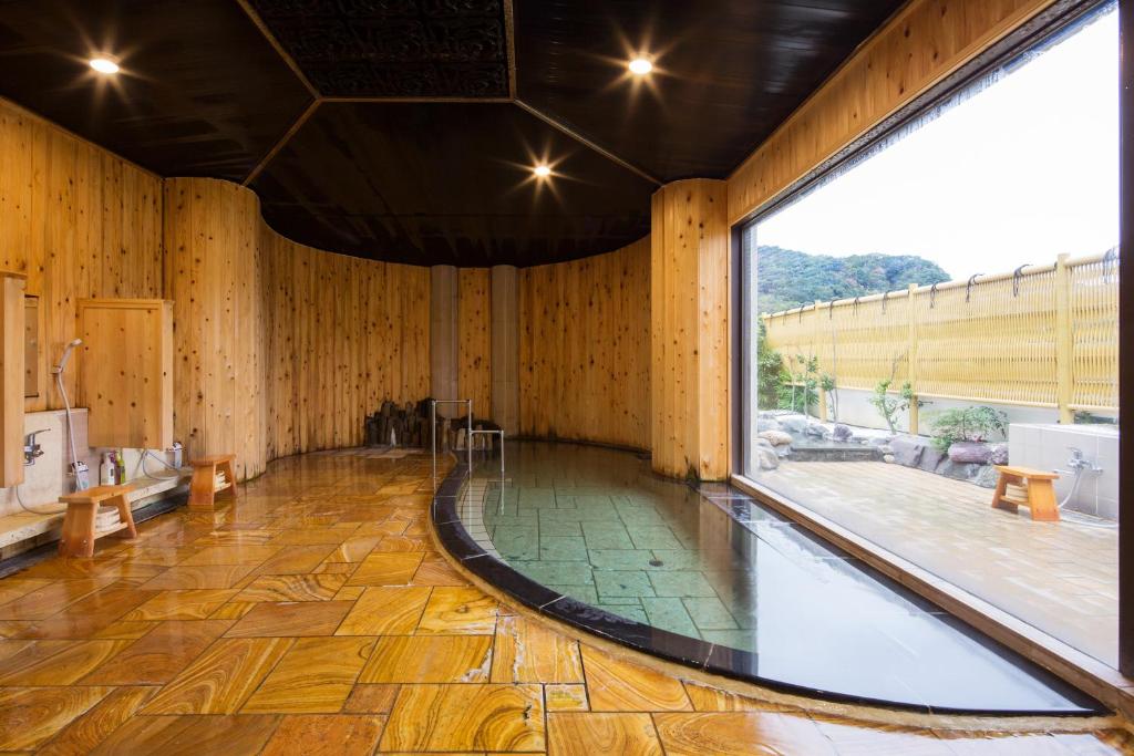 Cette grande chambre est dotée de murs en bois et d'une grande fenêtre. dans l'établissement Ishinoya Izunagaoka - TKP Hotels & Resorts, à Izunokuni