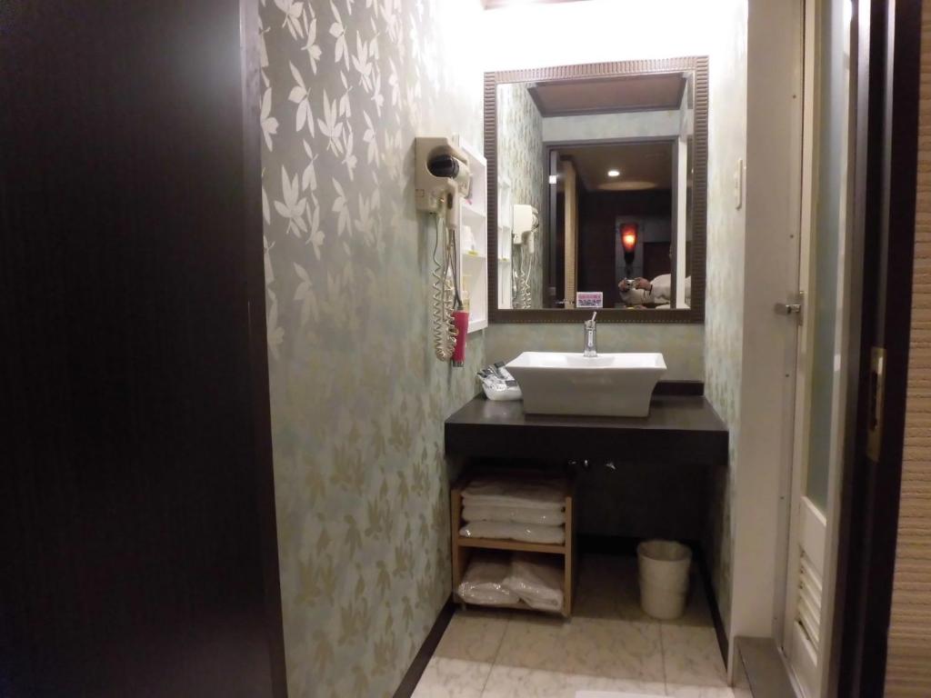 une salle de bain avec un lavabo et un miroir dans l'établissement ホテル タイムレス 明石 男塾ホテルグループ, à Akashi