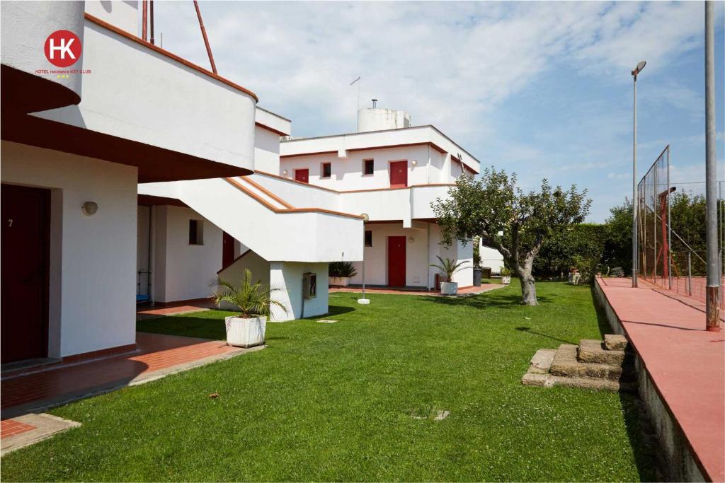 un bâtiment avec une cour avec de l'herbe verte dans l'établissement Hotel Residence Key Club, à Montalto di Castro