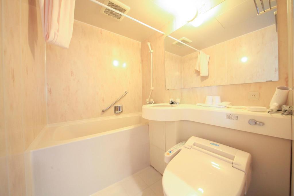 une salle de bain avec toilettes, baignoire et lavabo dans l'établissement Heiseikan Kaiyotei, à Hakodate