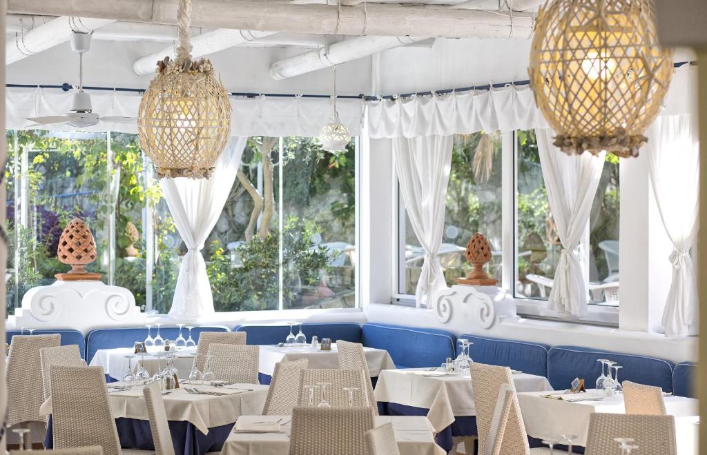 un restaurant avec des tables et des chaises blanches et des fenêtres dans l'établissement Hotel Terme Tritone Resort & Spa, à Ischia