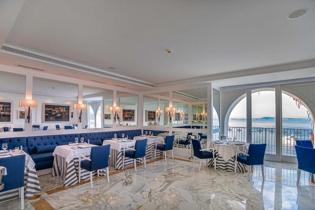 un restaurant avec des tables et des chaises et une vue sur l'océan dans l'établissement Grand Hotel Riviera, à Sorrente
