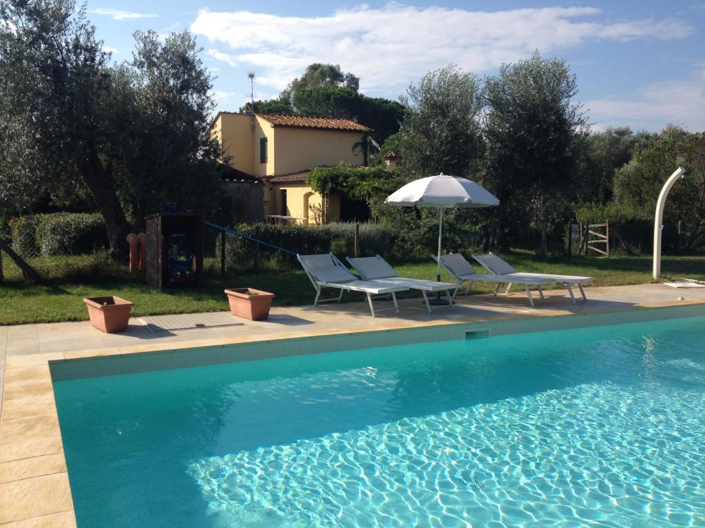 une piscine avec deux chaises et un parasol dans l'établissement La Toscanella, à Castagneto Carducci 7 autres photos