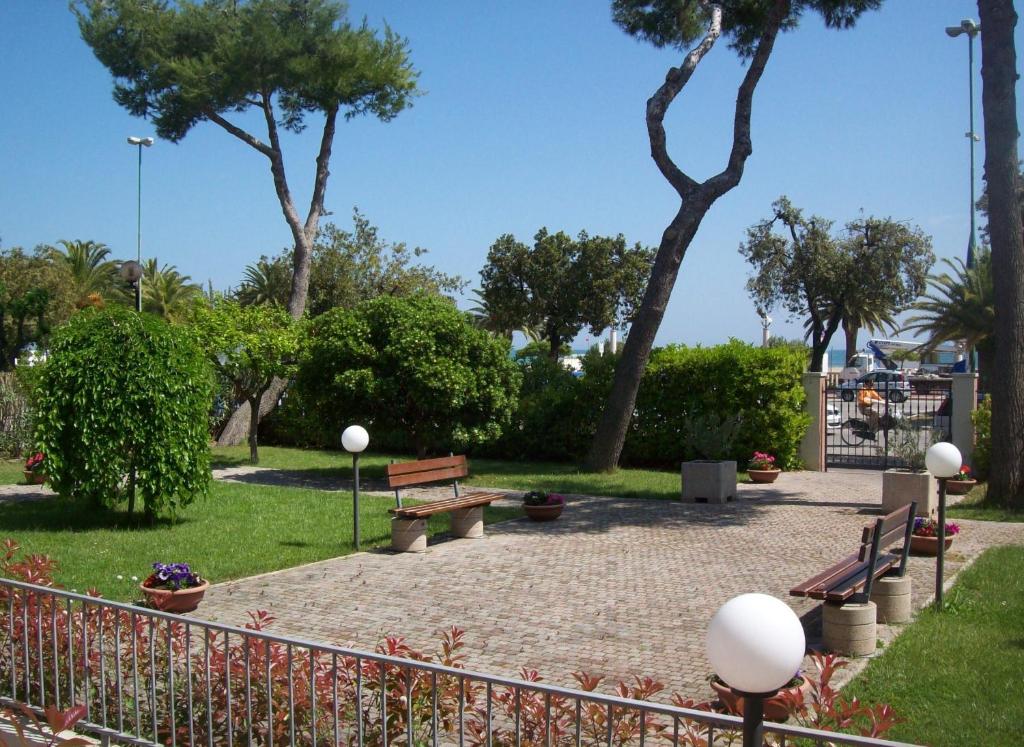 un parc avec des bancs, des arbres et une clôture dans l'établissement Hotel Sole, à Giulianova