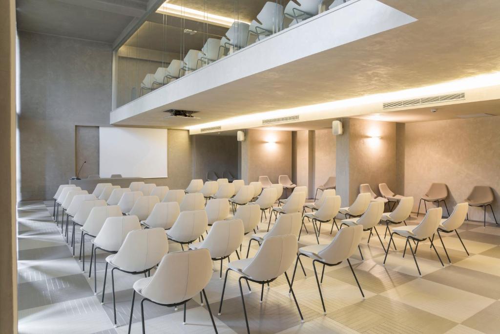 une salle de conférence avec des chaises blanches et un podium dans l'établissement Roccamare Resort - Casa di Ponente, à Castiglione della Pescaia 94 autres photos
