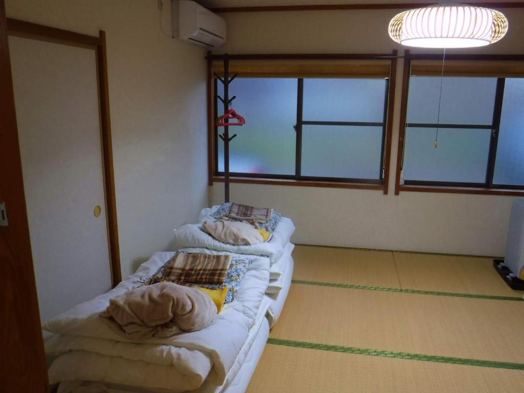 - une chambre avec 2 lits dans une chambre avec fenêtres dans l'établissement Wholeearth Ryokan Hiroshima, à Hiroshima 37 autres photos
