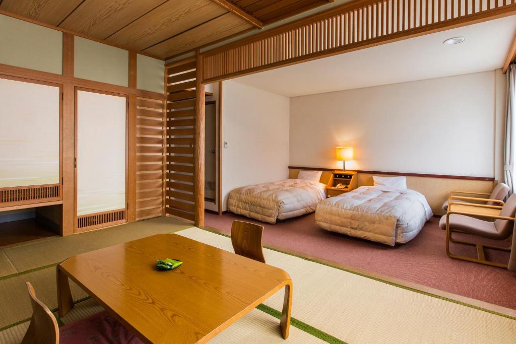 une chambre d'hôtel avec deux lits et une table dans l'établissement Choyo Tei, à Kamikawa