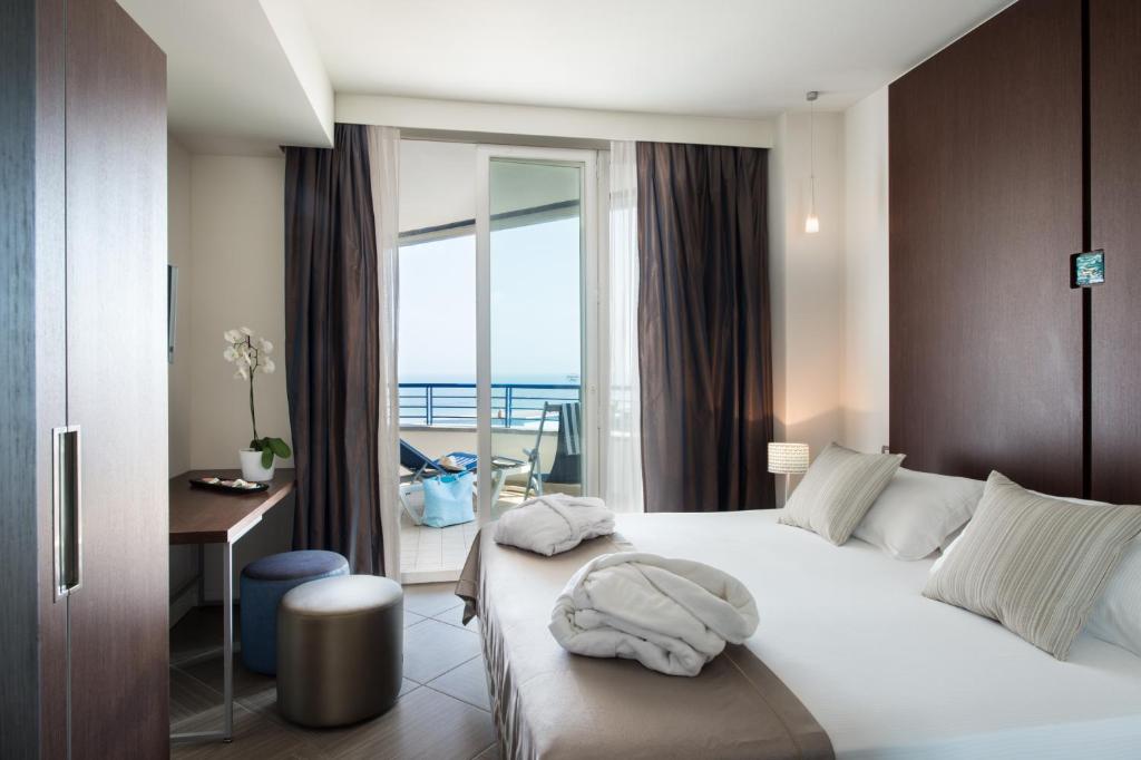 une chambre avec un lit et un bureau et un balcon dans l'établissement Blu Suite Resort, à Bellaria-Igea Marina