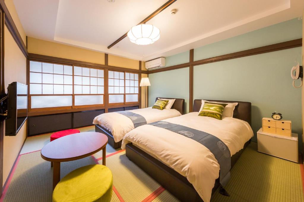 - 2 lits dans une chambre avec une table et un tabouret dans l'établissement Hanaingen, à Kusatsu