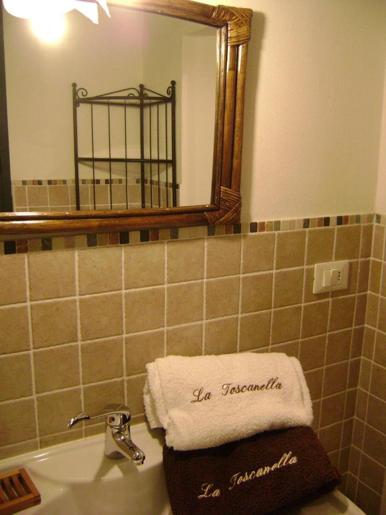 La salle de bains est pourvue d'un miroir et d'une serviette sur un lavabo. dans l'établissement La Toscanella, à Castagneto Carducci
