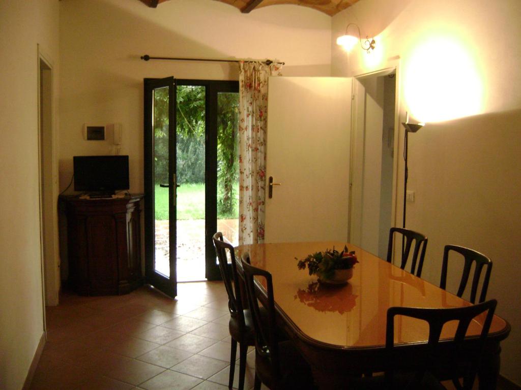 une salle à manger avec une table, des chaises et une télévision dans l'établissement La Toscanella, à Castagneto Carducci
