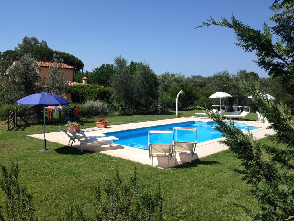 une piscine avec deux chaises et un parasol dans l'établissement La Toscanella, à Castagneto Carducci