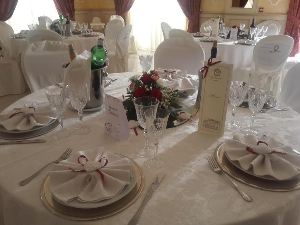 une table avec des assiettes, des serviettes et des verres à vin dessus dans l'établissement Hotel Villa Santa Maria, à Villapiana