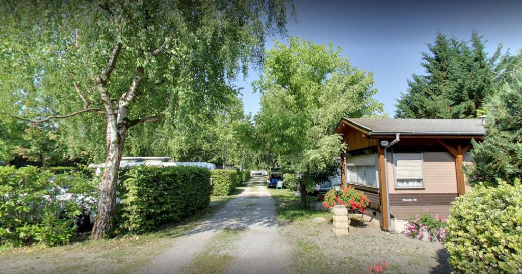 une allée menant à une maison ornée d'arbres et de fleurs dans l'établissement Camping la Chaumière, à Heimsbrunn