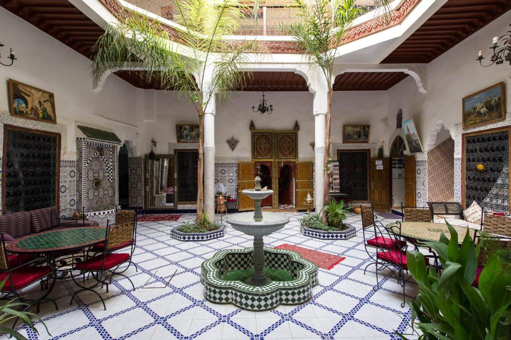 une cour avec une fontaine, des tables et des chaises dans l'établissement Riad Chennaoui, à Marrakech