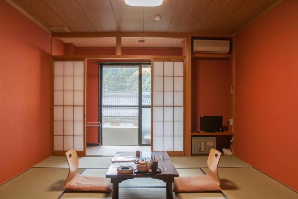 Cette chambre est dotée de murs orange, d'une table et de chaises. dans l'établissement 湖上館パムコ, à Wakasa